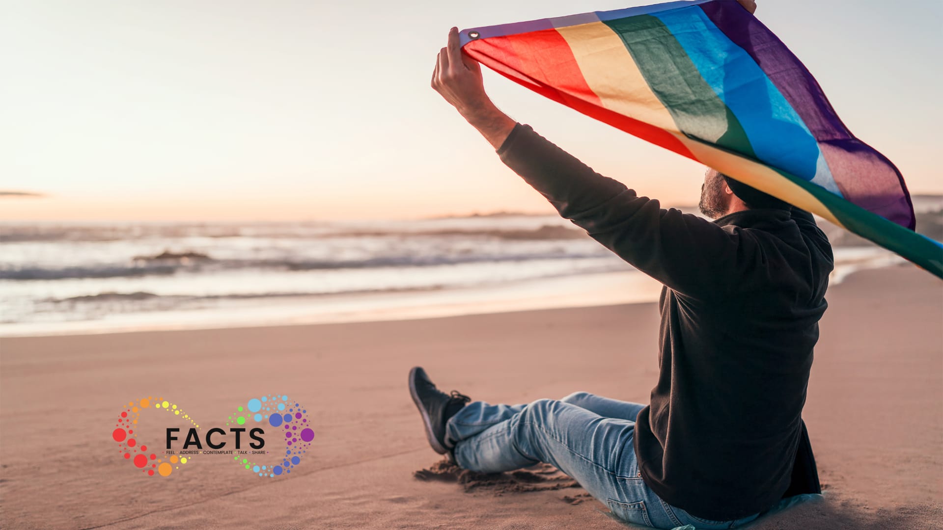 Henkilö istuu rannalla staeenkaarilipun kanssa