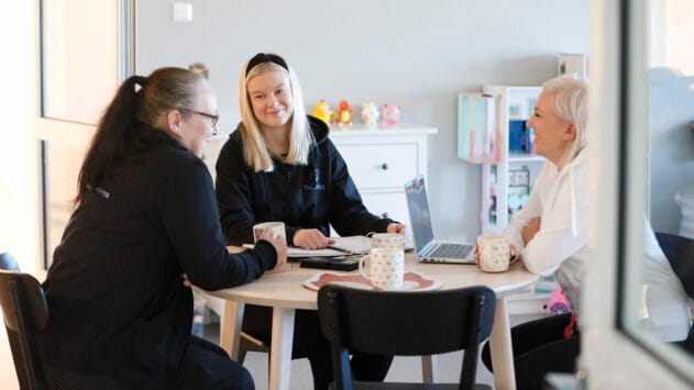Kolme Tukenan työntekijää keskustelee pöydän äärellä
